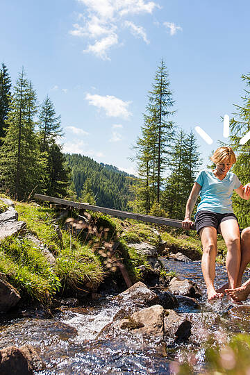 Wanderer überqueren eine kleine Brücke über einen Bergbach in den Nockbergen © Franz Gerdl_MBN Tourismus