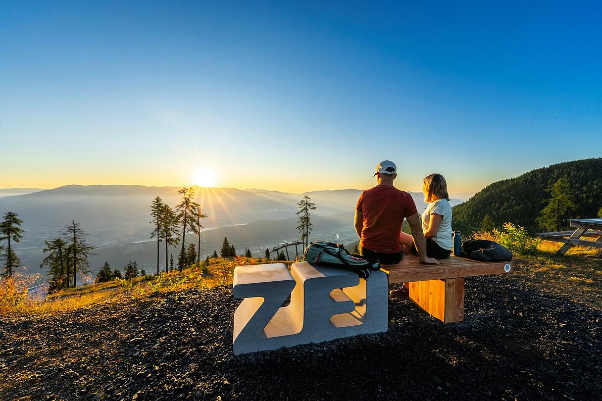 ZEIT zu zweit bei Sonnenuntergang am Sportberg Goldeck genießen Pärchen sitzt auf Zeitbank am Goldeck und genießt den Ausblick